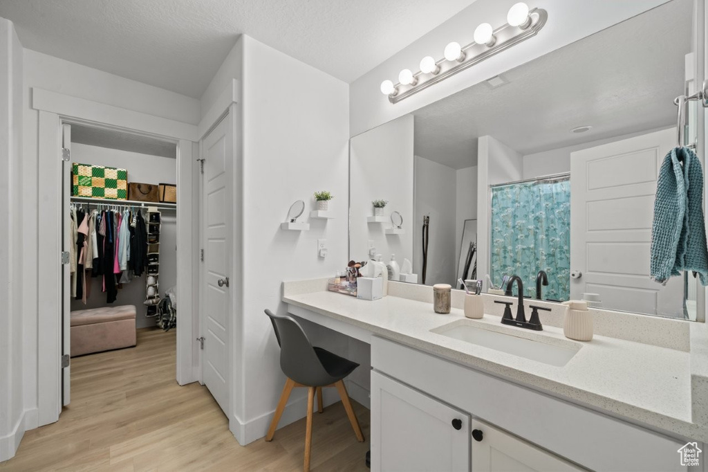 Full bathroom with wood finished floors, vanity, a spacious closet, and a shower with shower curtain