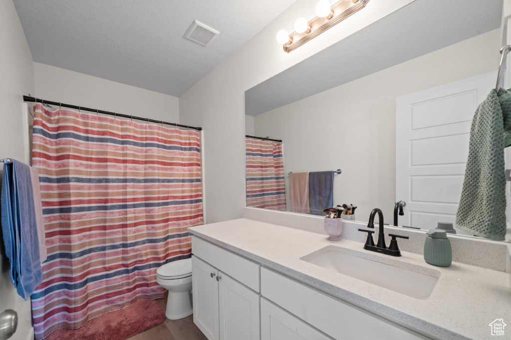 Full bath featuring vanity, wood finished floors, and curtained shower