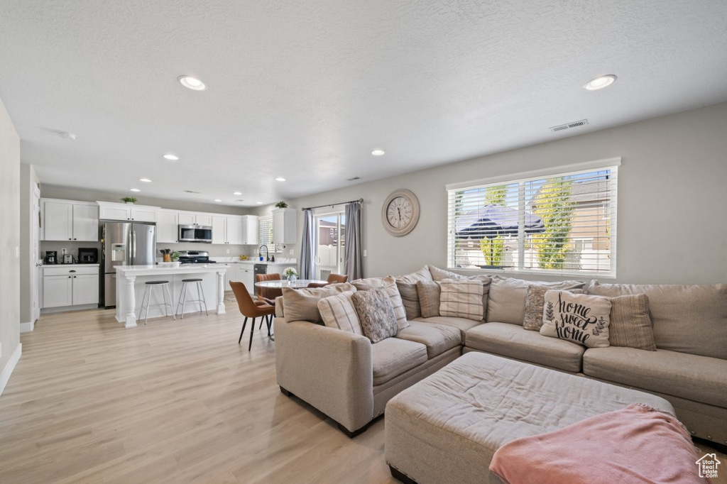 Living area with light wood-style flooring and recessed lighting