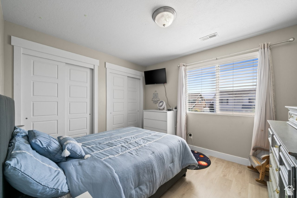 Bedroom with light wood finished floors and two closets