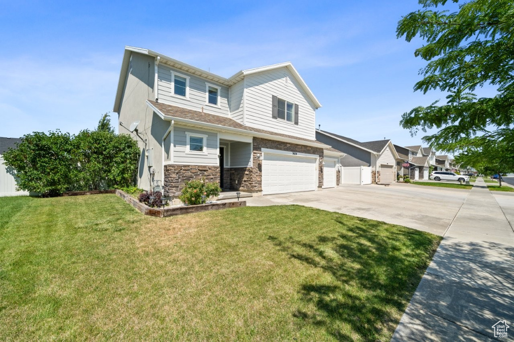 View of front facade featuring concrete driveway, an attached garage, a front lawn, and stone siding