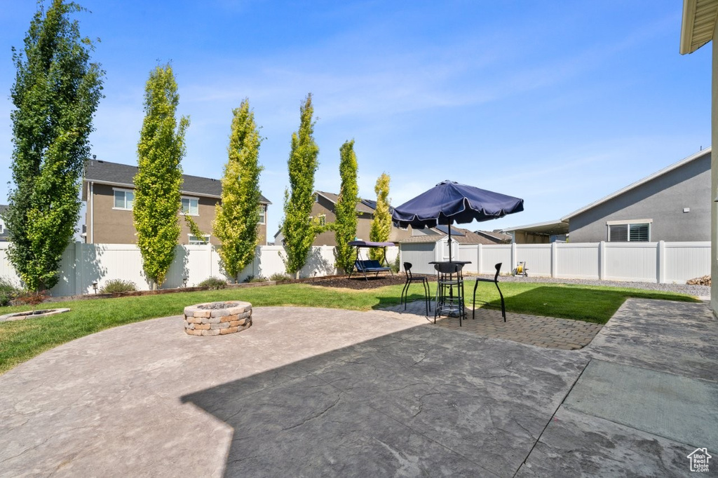 Fenced backyard featuring an outdoor fire pit, a patio, a residential view, and outdoor dining area