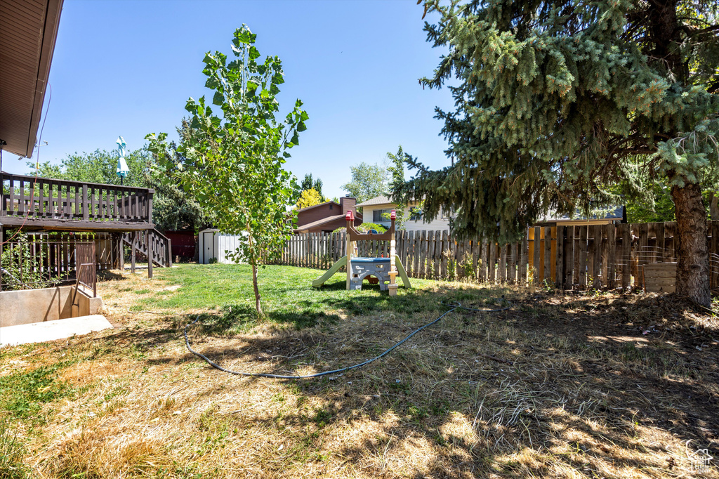 Fenced backyard with a storage shed, a deck, and stairway