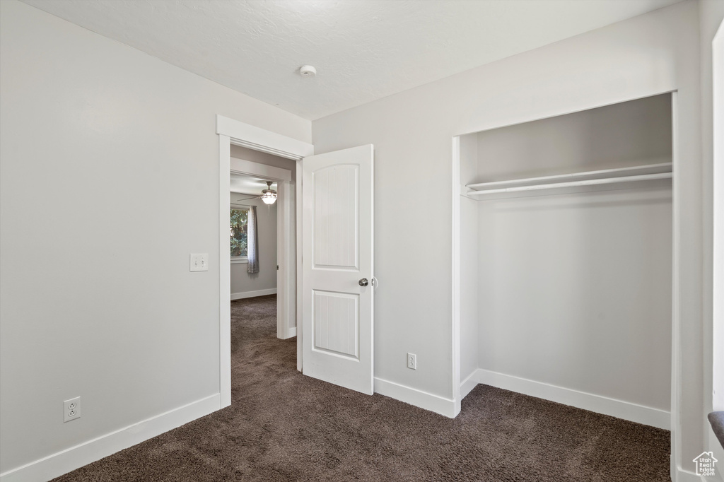 Unfurnished bedroom with dark colored carpet and a closet