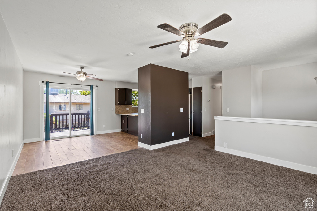 Unfurnished living room featuring a ceiling fan and carpet