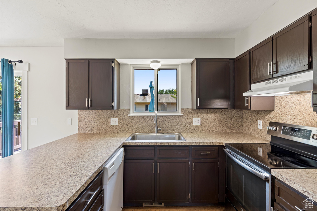 Kitchen featuring appliances with stainless steel finishes, under cabinet range hood, a peninsula, and plenty of natural light