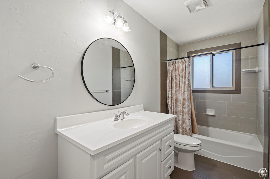 Bathroom with vanity, shower / bath combo, and wood finished floors