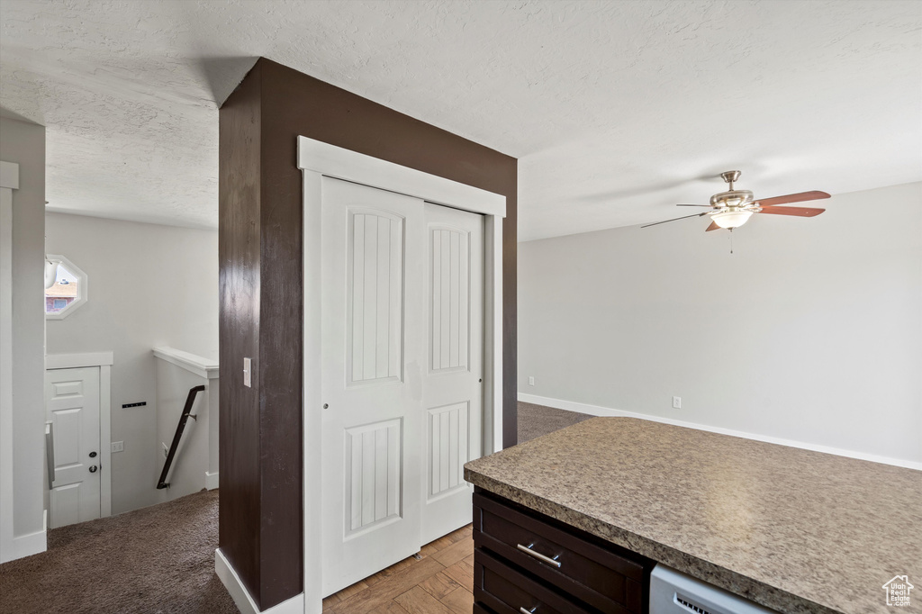 Kitchen featuring a textured ceiling, ceiling fan, and dark brown cabinets