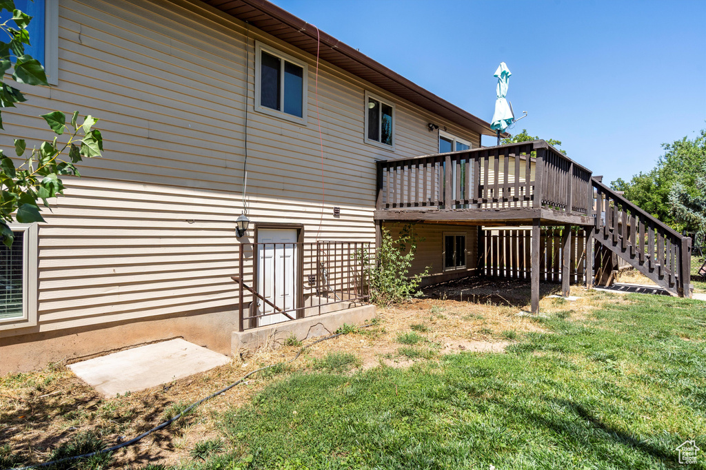 Back of house with a wooden deck, stairs, and a lawn
