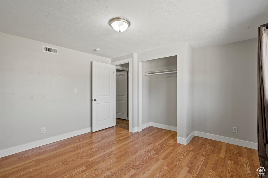 Unfurnished bedroom with light wood-style flooring and a closet