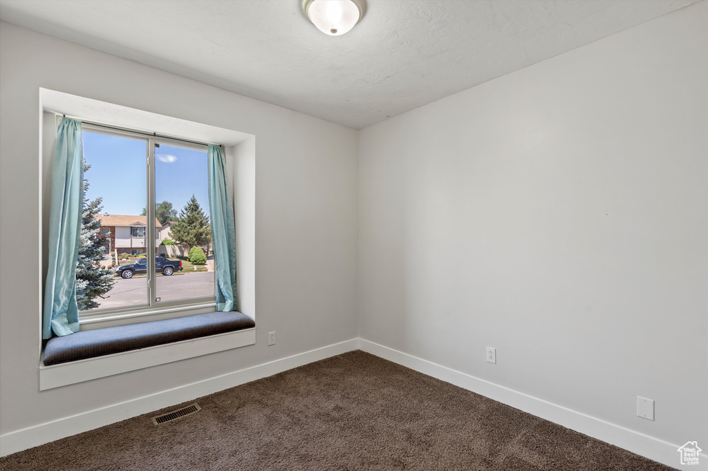Spare room featuring baseboards and dark carpet