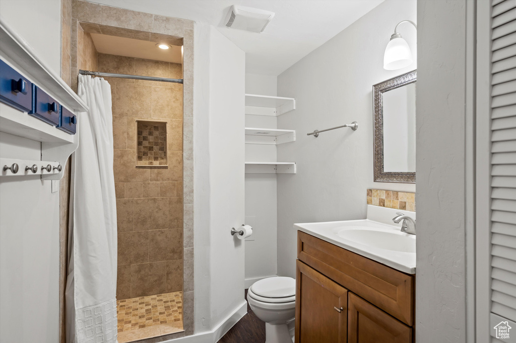 Full bath featuring vanity, a tile shower, and wood finished floors
