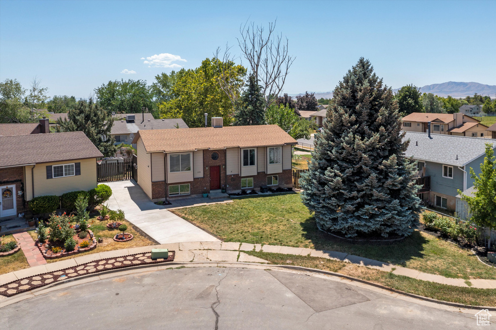 Split foyer home featuring brick siding, a residential view, a gate, concrete driveway, and a mountain view
