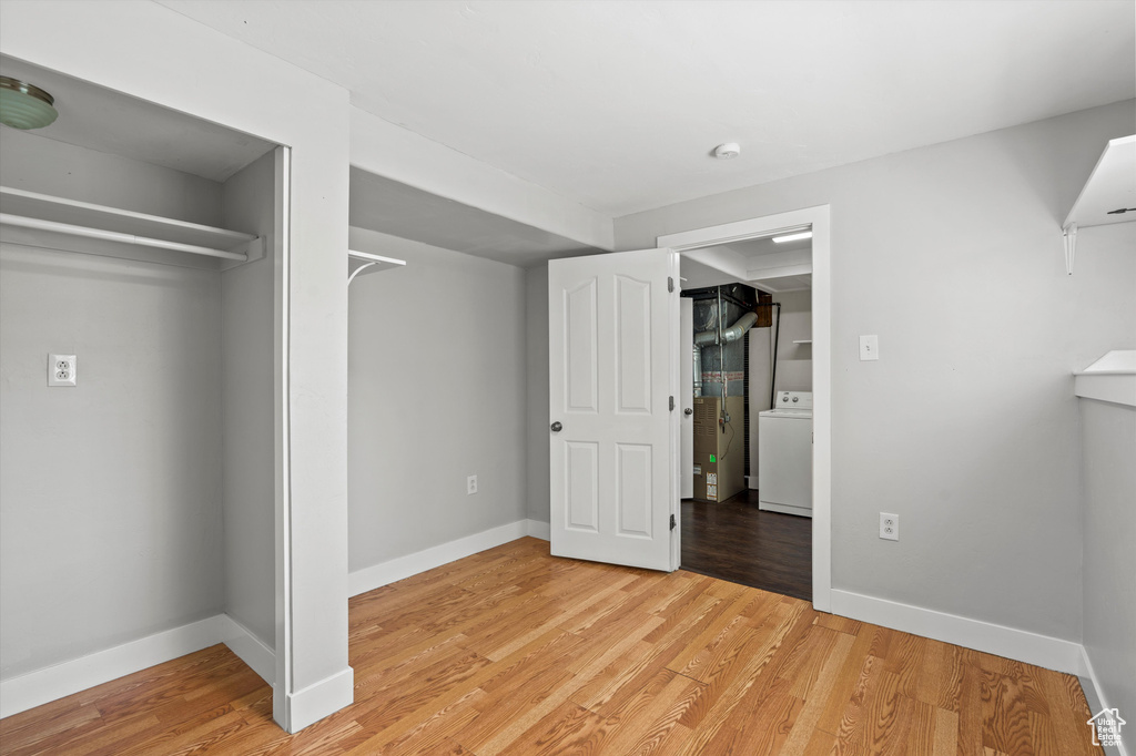 Unfurnished bedroom featuring washer / clothes dryer and light wood-style flooring