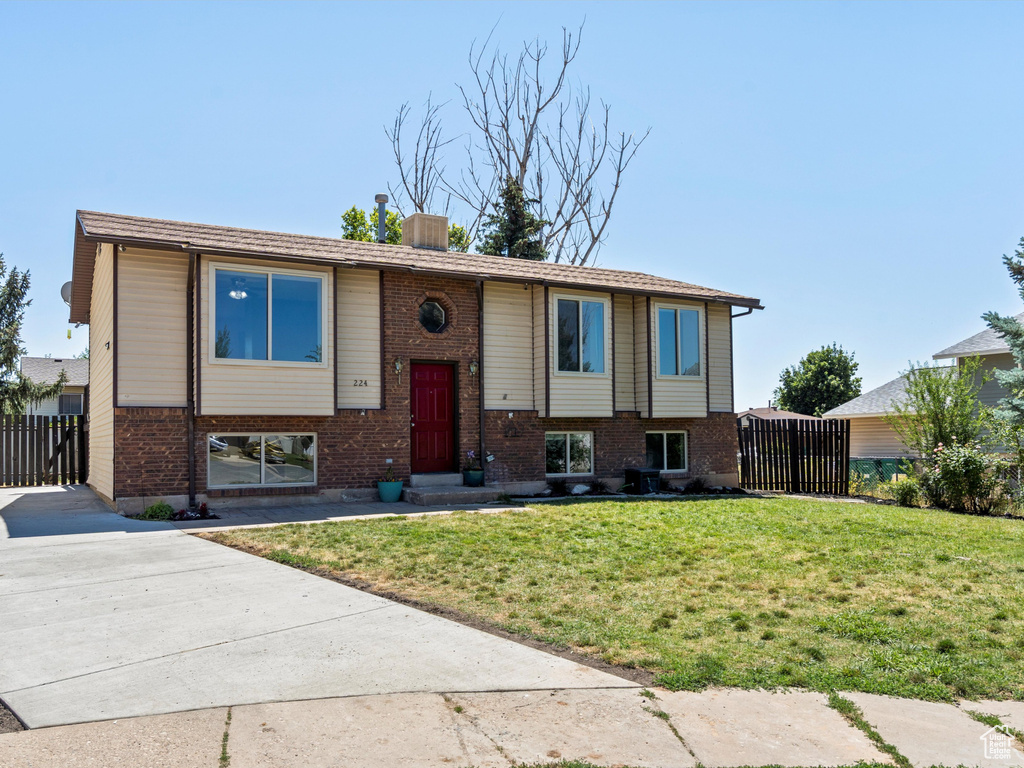 Split foyer home featuring driveway, brick siding, and a chimney