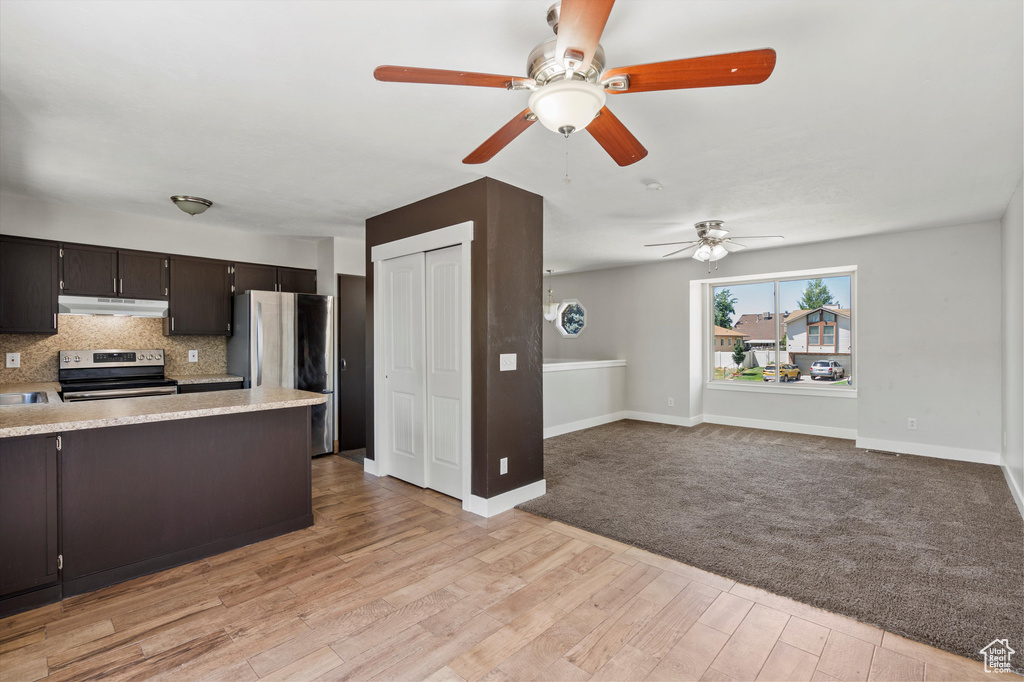 Kitchen featuring appliances with stainless steel finishes, a ceiling fan, under cabinet range hood, decorative backsplash, and a peninsula