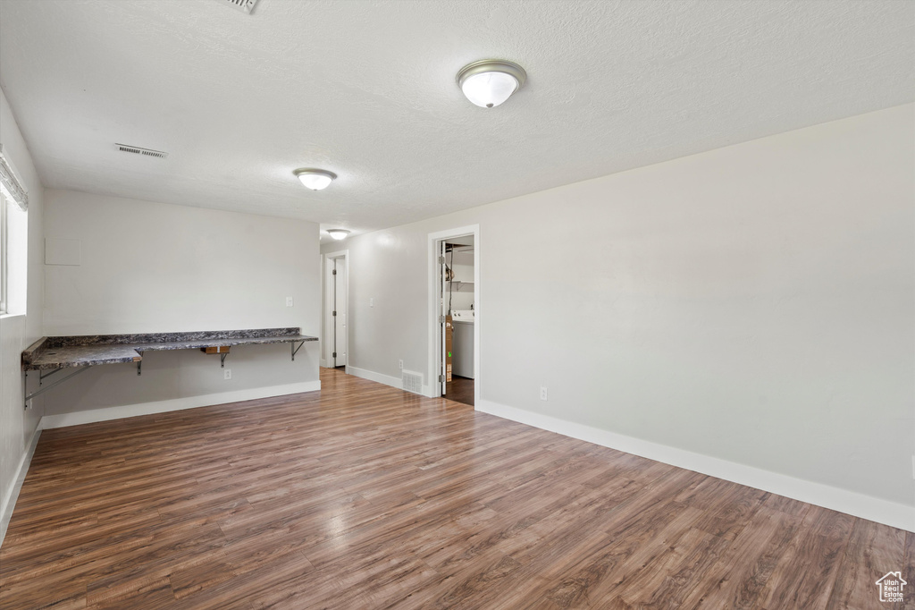 Unfurnished room with wood finished floors and a textured ceiling
