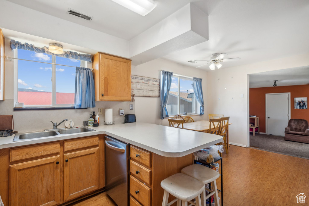 Kitchen with stainless steel dishwasher, a peninsula, light countertops, a kitchen breakfast bar, and a ceiling fan