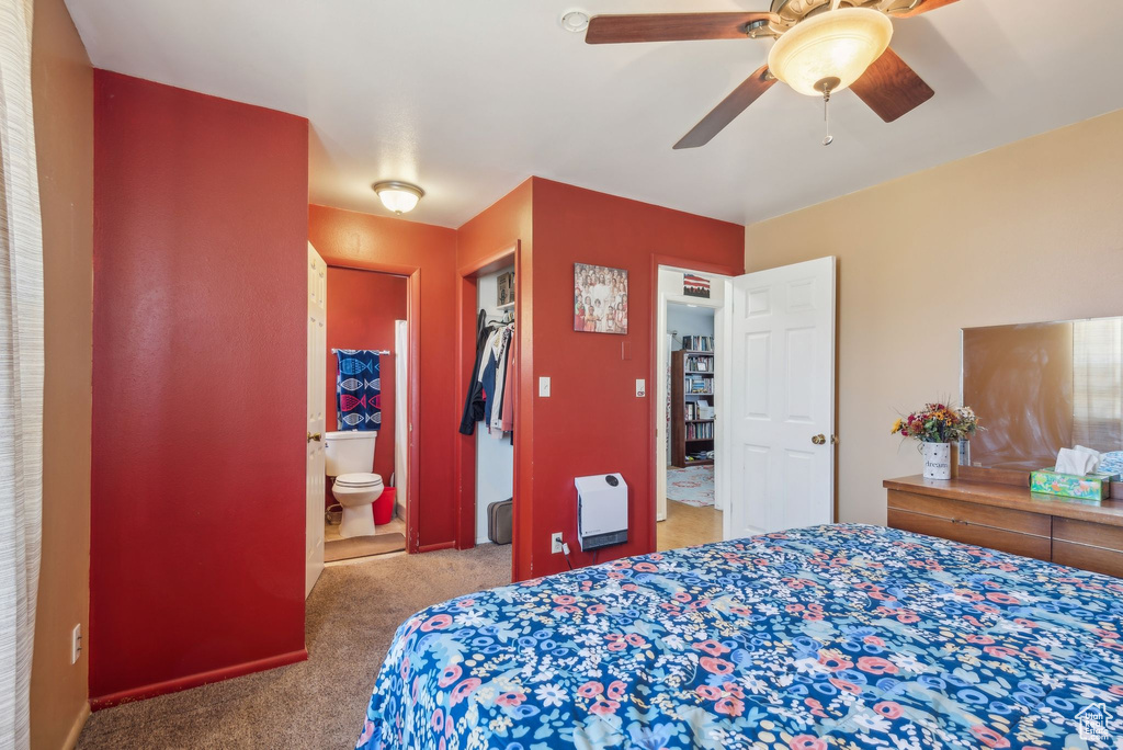 Carpeted bedroom with ensuite bath, ceiling fan, heating unit, and a closet