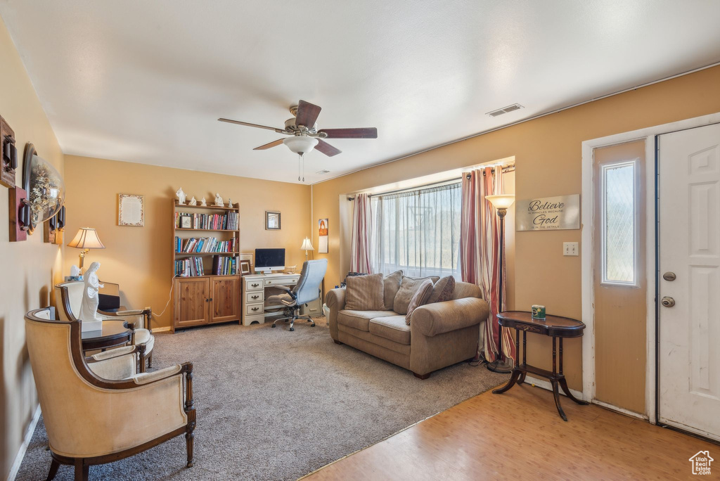 Living room with a desk, a ceiling fan, and wood finished floors