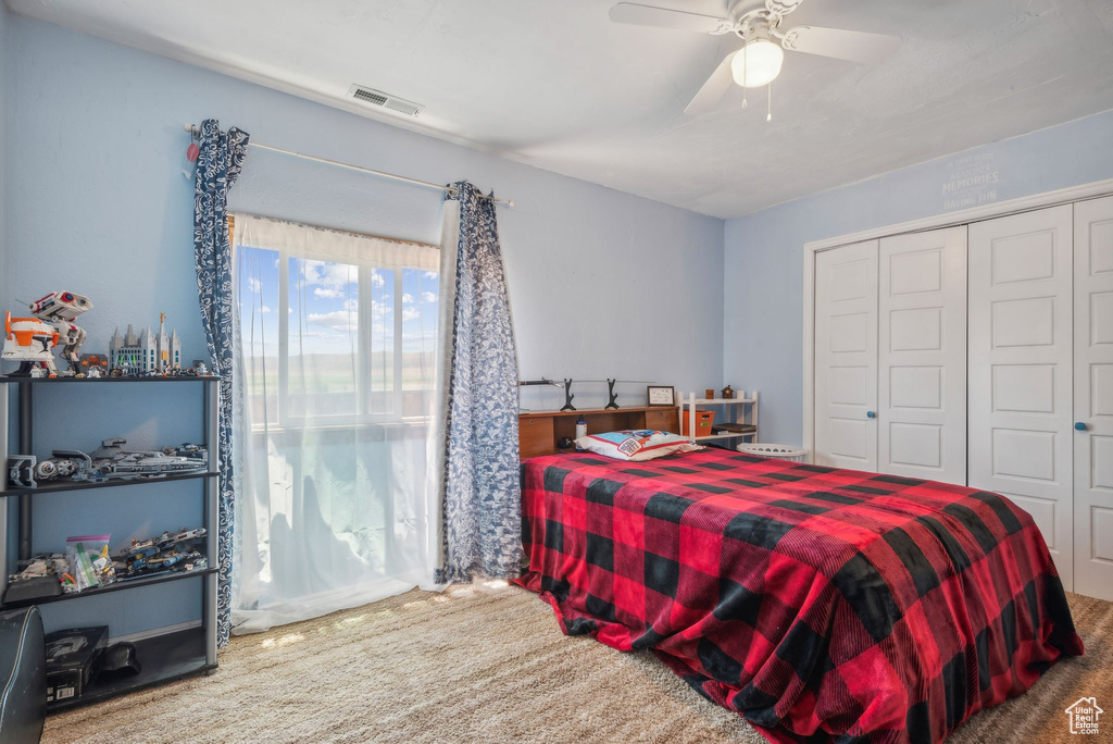 Carpeted bedroom featuring a closet and ceiling fan