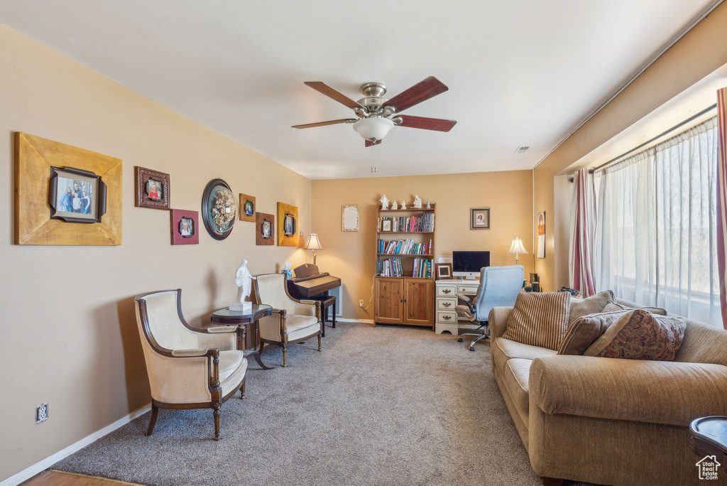Living area with a desk, ceiling fan, and carpet