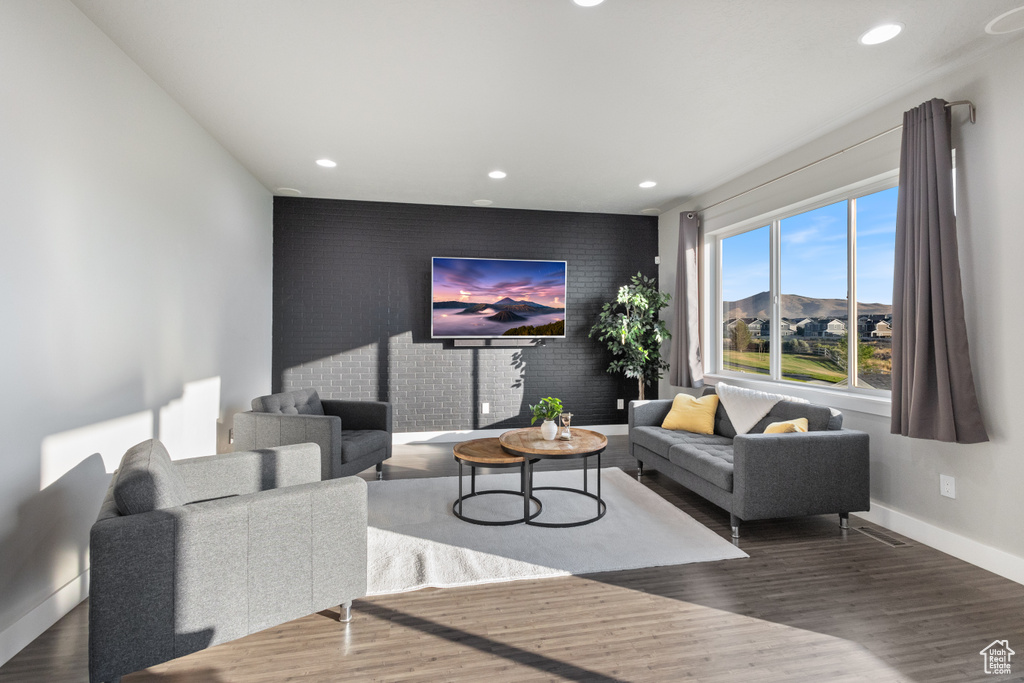Living room with an accent wall, recessed lighting, and wood finished floors