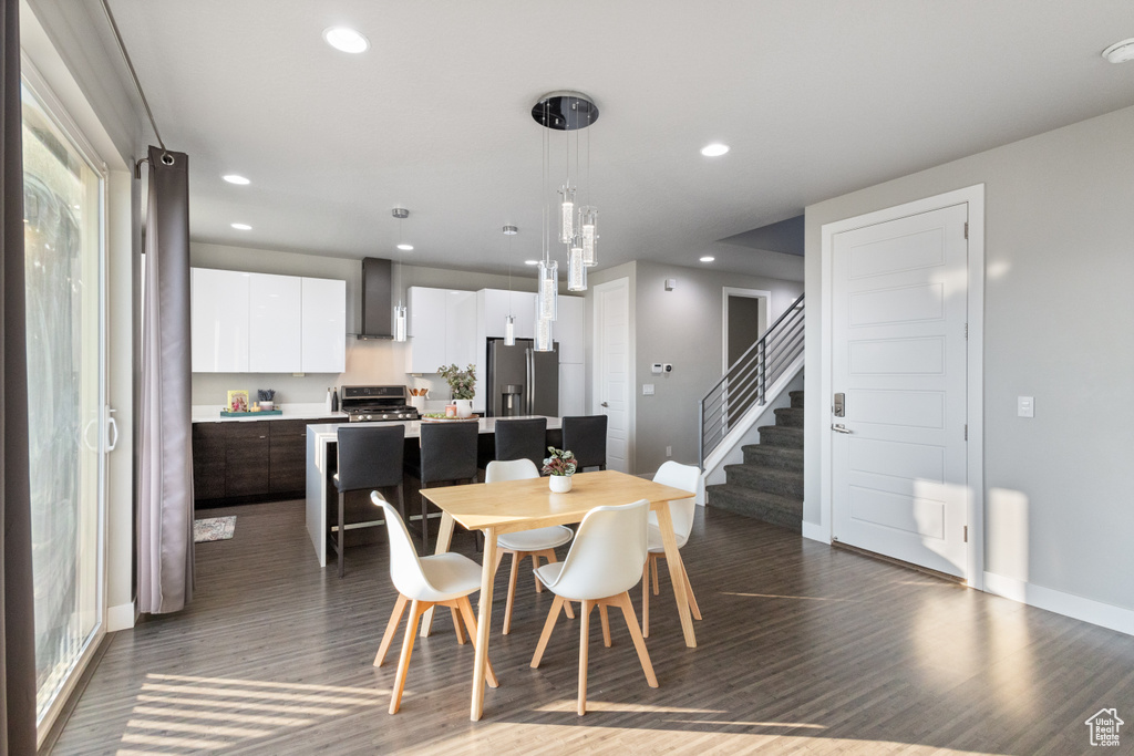 Dining space with dark wood-style floors, recessed lighting, and stairs
