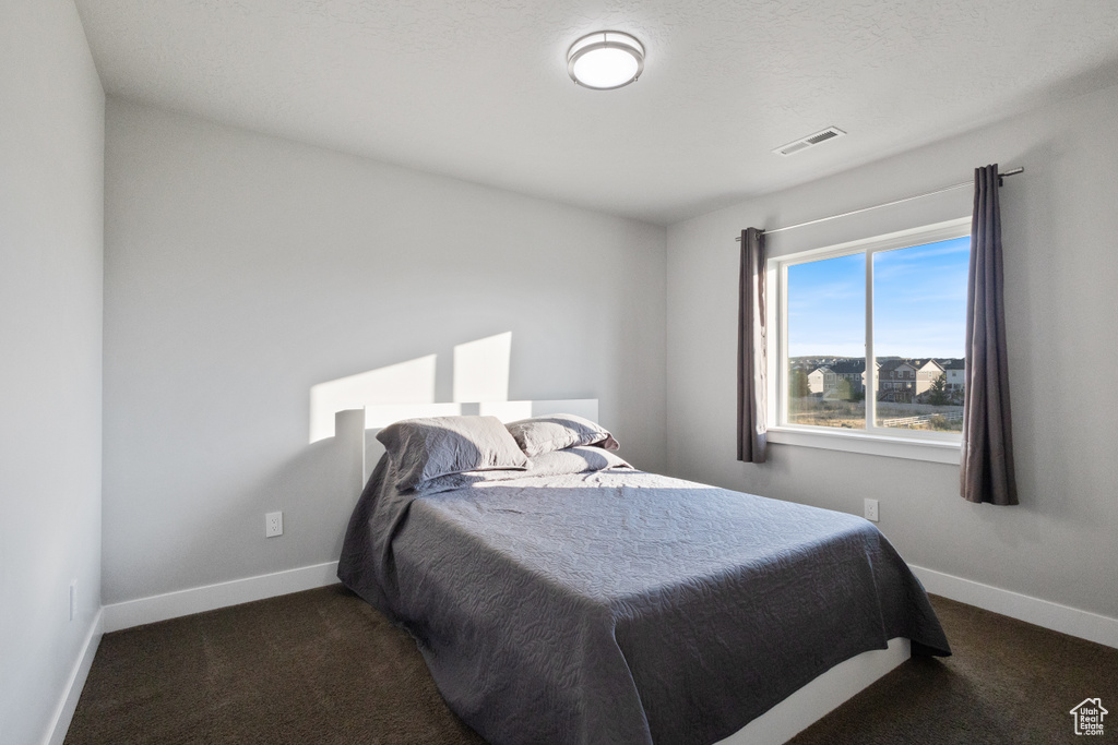 Bedroom featuring dark colored carpet and baseboards