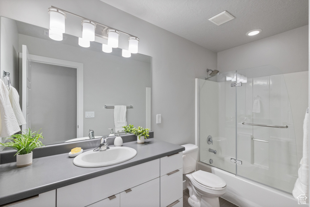 Bathroom with vanity, bath / shower combo with glass door, a textured ceiling, and recessed lighting