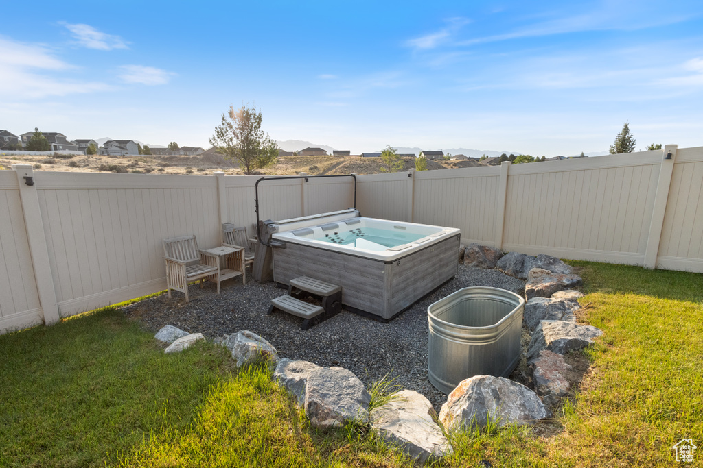 Fenced backyard featuring a hot tub