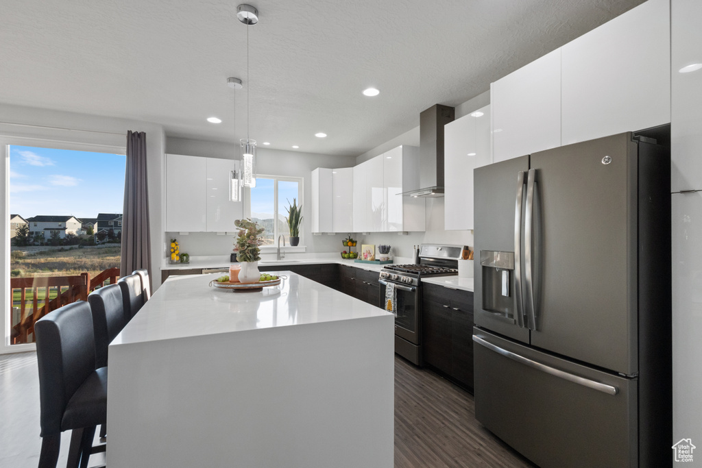 Kitchen with stainless steel appliances, wall chimney exhaust hood, modern cabinets, white cabinetry, and recessed lighting