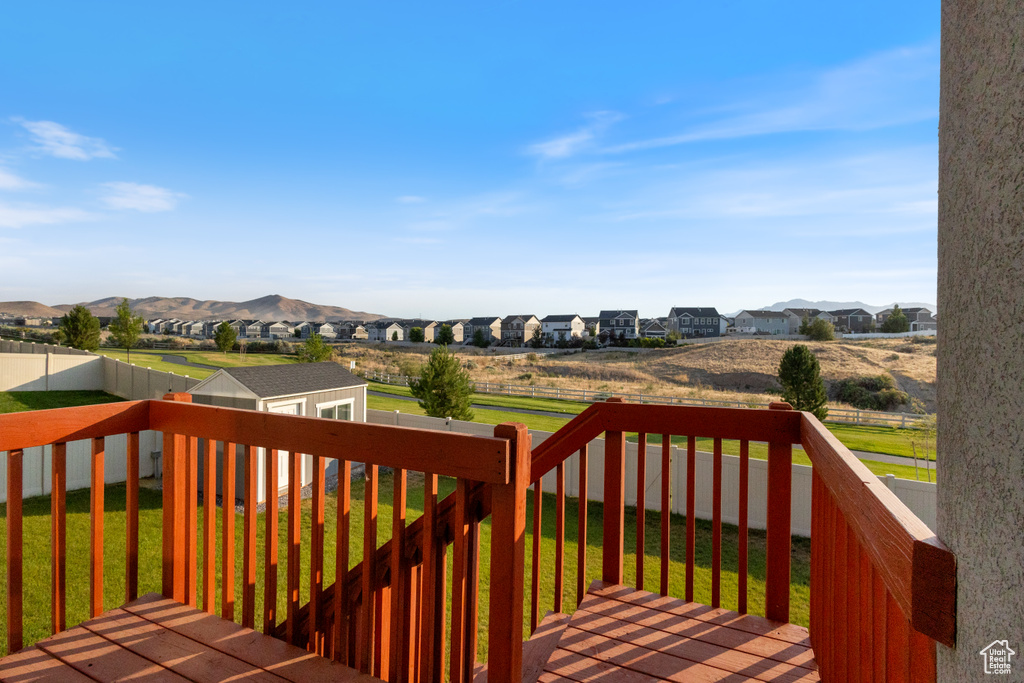 Wooden terrace featuring an outbuilding, a fenced backyard, a residential view, and a mountain view