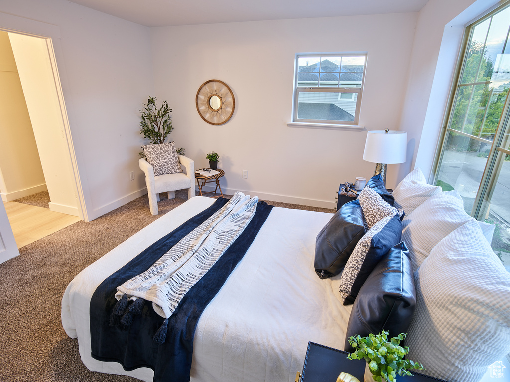 Carpeted bedroom with baseboards and access to exterior