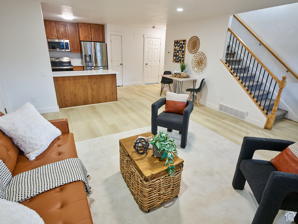Living area with light wood-style floors, stairway, and recessed lighting