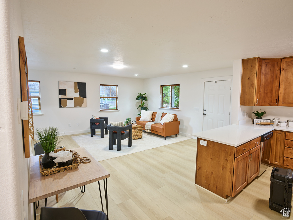 Kitchen with dishwashing machine, open floor plan, light wood-type flooring, brown cabinetry, and light countertops