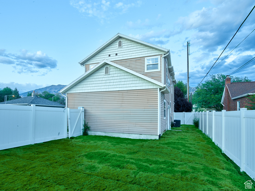View of side of home with a fenced backyard and a central AC unit