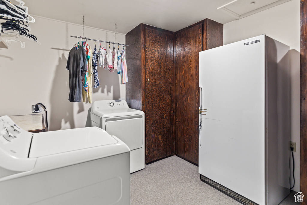 Laundry area with washer and clothes dryer, light colored carpet, and cabinet space