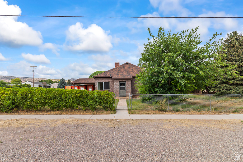 View of front of property with a fenced front yard, brick siding, and a chimney