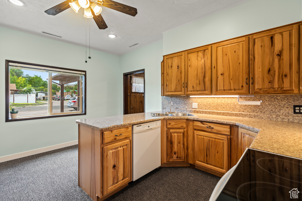 Kitchen featuring dishwasher, dark carpet, brown cabinets, and recessed lighting