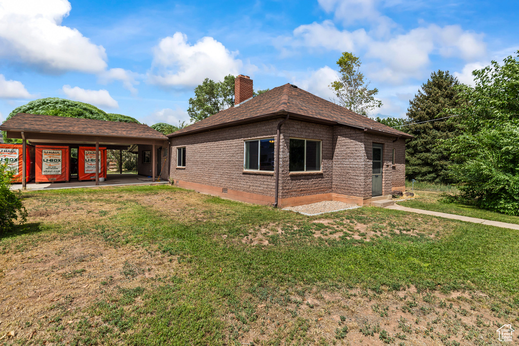Rear view of property with a chimney, a lawn, and brick siding