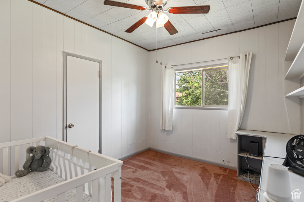 Bedroom with light colored carpet, ceiling fan, and a crib