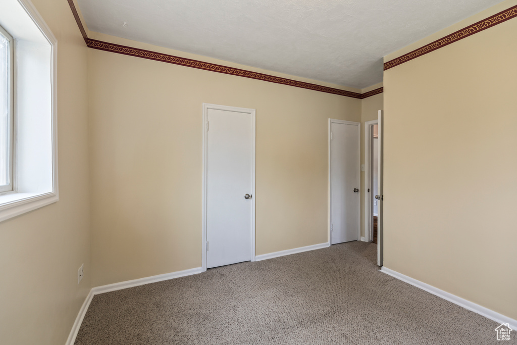 Carpeted spare room featuring baseboards