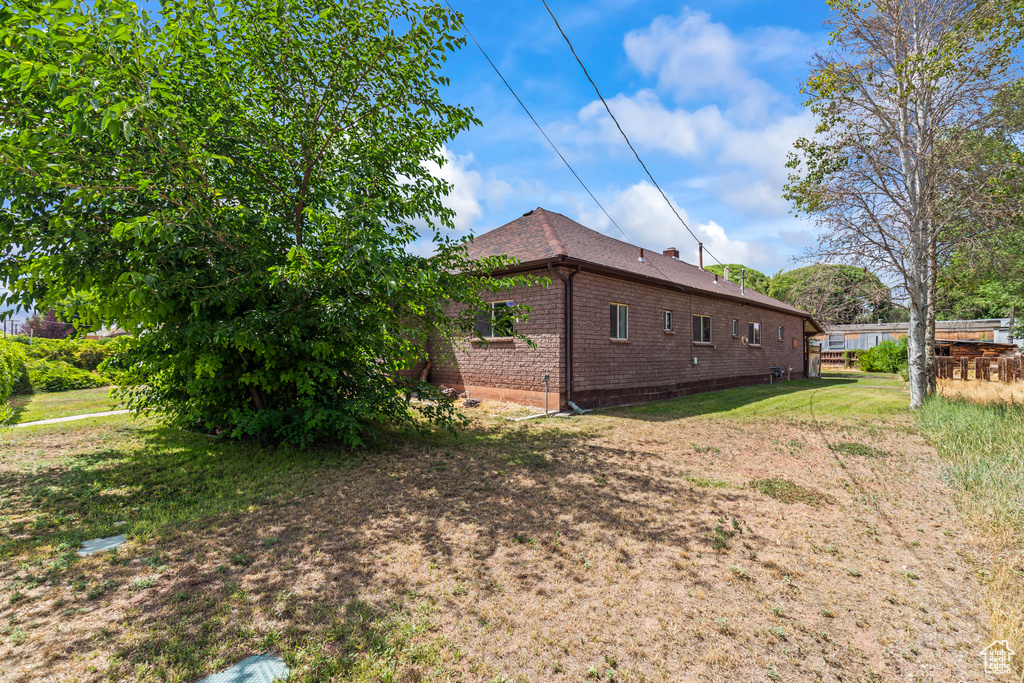 View of property exterior with brick siding and a yard