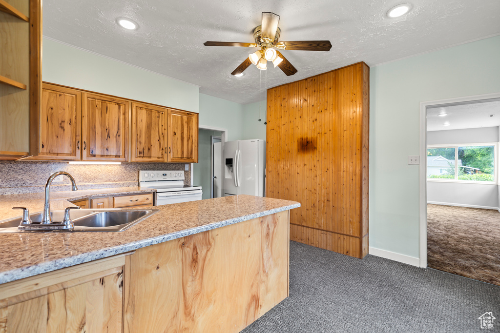 Kitchen with white appliances, dark carpet, a ceiling fan, a peninsula, and a textured ceiling