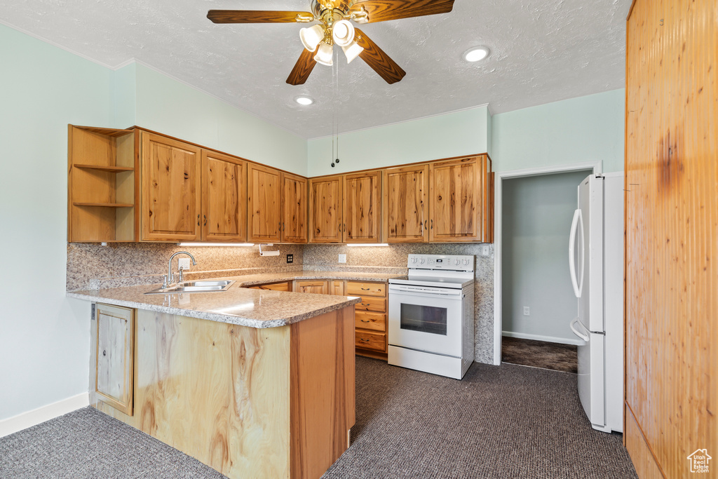Kitchen featuring white appliances, dark carpet, a peninsula, tasteful backsplash, and a textured ceiling