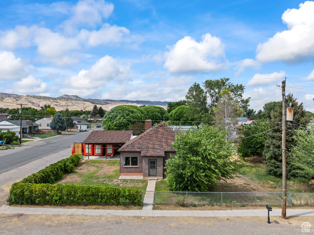 View of front of home with brick siding, a shingled roof, a mountain view, and a chimney