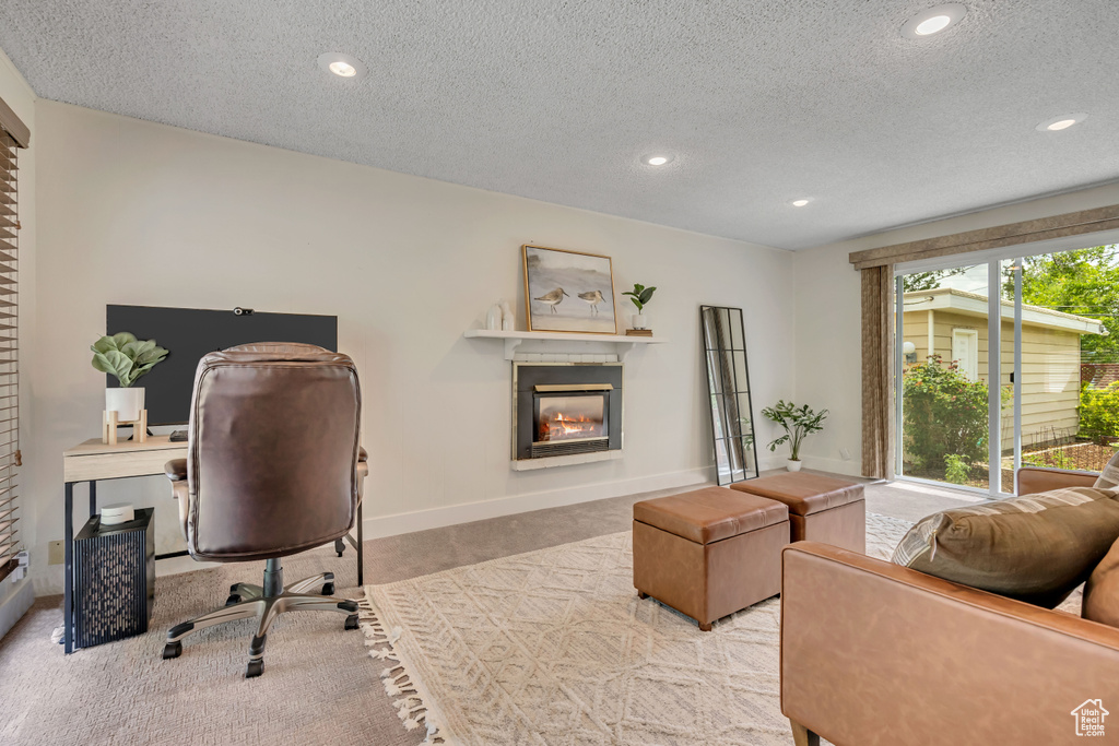 Carpeted home office featuring a glass covered fireplace, a textured ceiling, and recessed lighting