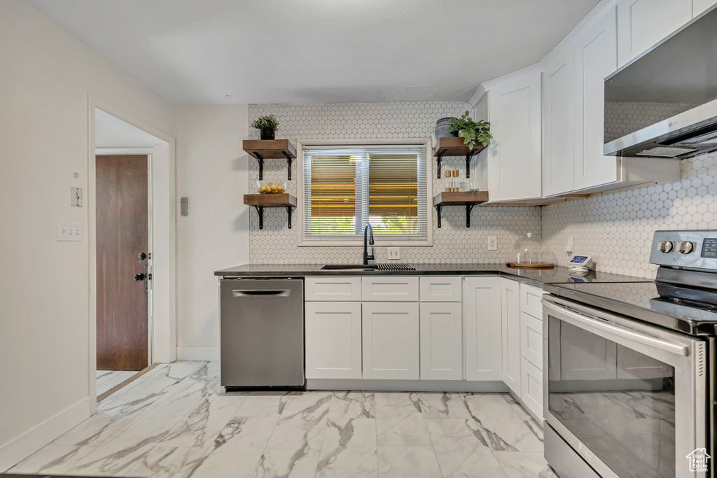 Kitchen featuring stainless steel appliances, open shelves, light marble finish flooring, and white cabinetry