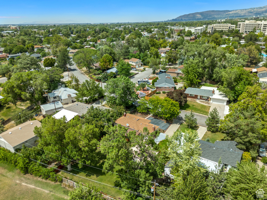 Aerial perspective of suburban area featuring a mountain backdrop and a tree filled landscape
